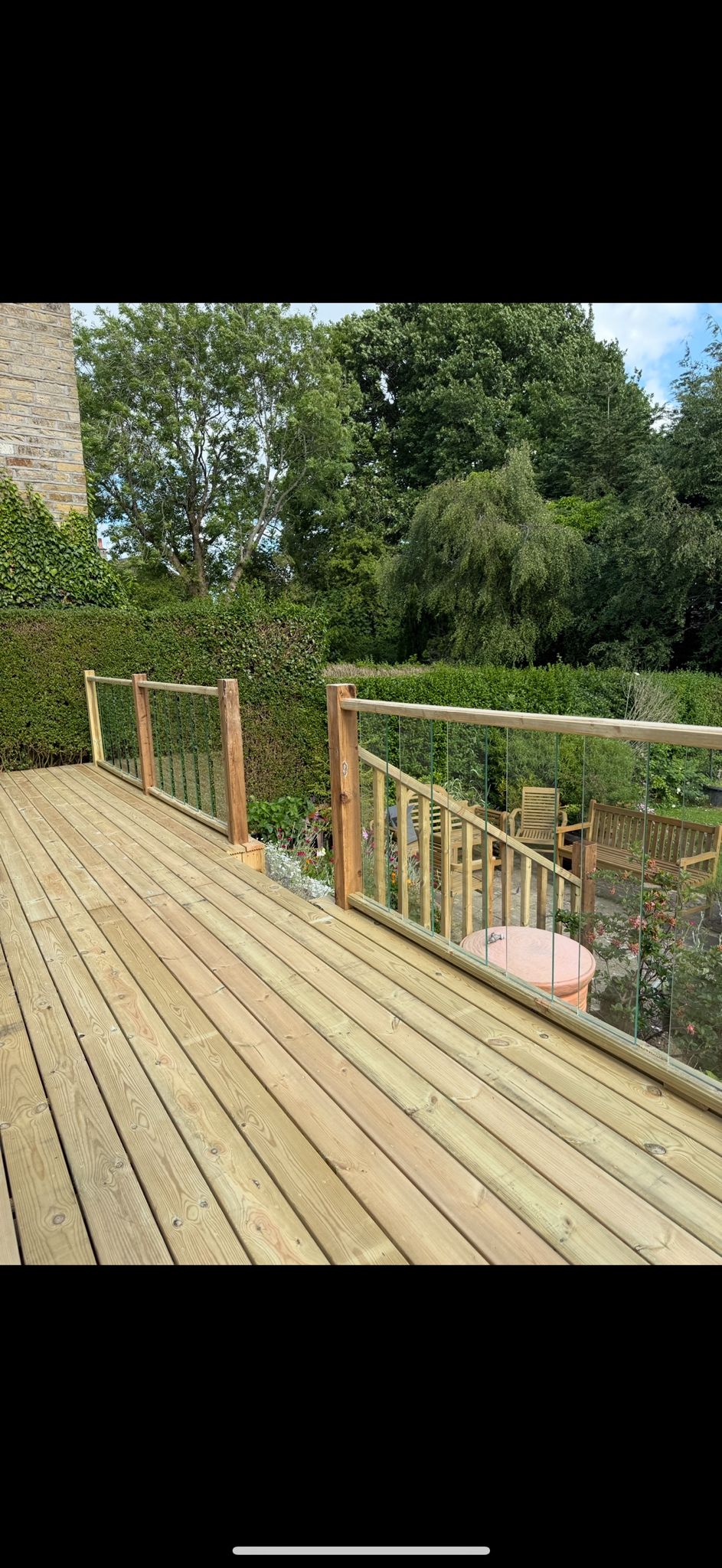 Timber decking with glass balustrade overlooking garden